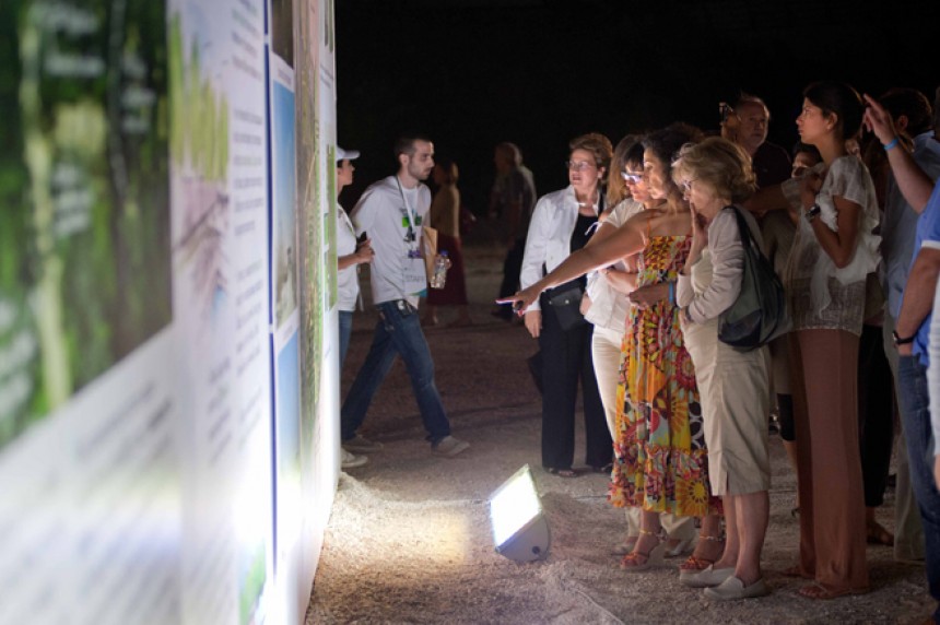 Κόσμος κοιτάει μια φωτογραφία που υπάρχει σε έναμ τοίχο τοποθετημένο σε έναν εξωτερικό χώρο