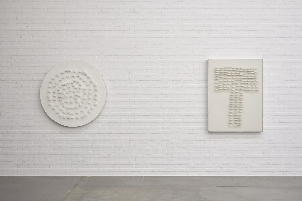 Δύο έργα τέχνης τοποθετημένα πάνω σε έναν τούβλινο τοίχο