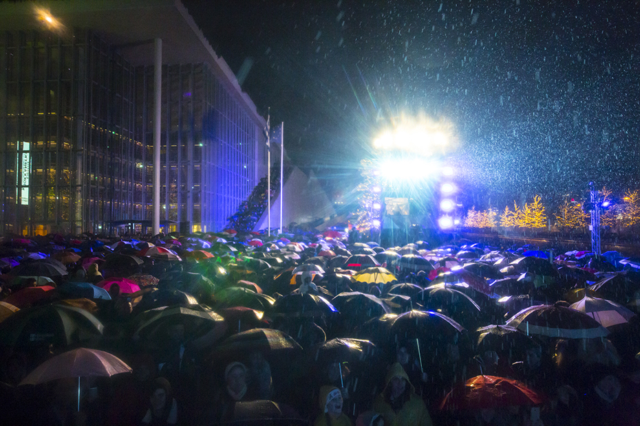 Πλήθος ανθρώπων που κρατούν ομπρέλες συγκεντρώνονται την παραμονή της Πρωτοχρονιάς στο Κέντρο Πολιτισμού Ίδρυμα Σταύρος Νιάρχος