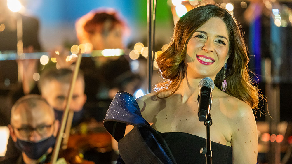 Μια γυναίκα χαμογελά μπροστά σε μια ορχήστρα