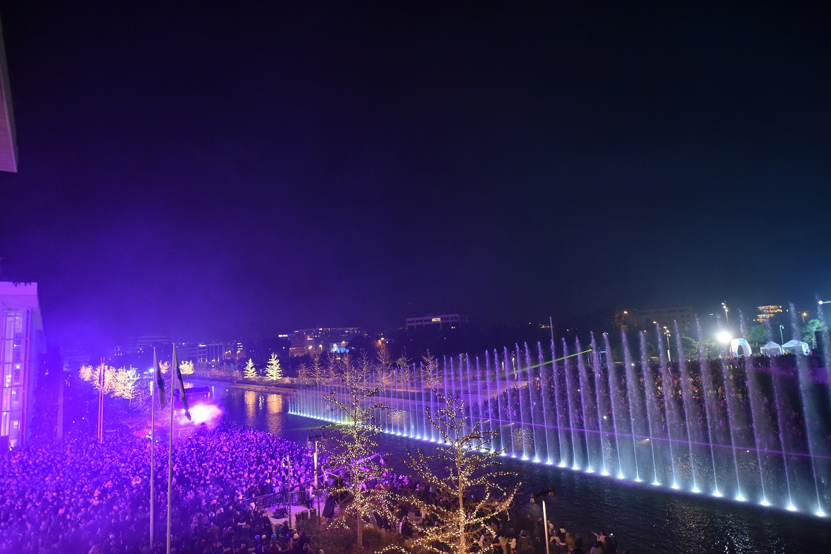 Φωτογραφία τραβηγμένη το βράδυ που δείχνει μια λίμνη στο κέντρο της οποίας το συντριβάνι κάνει ένα show  