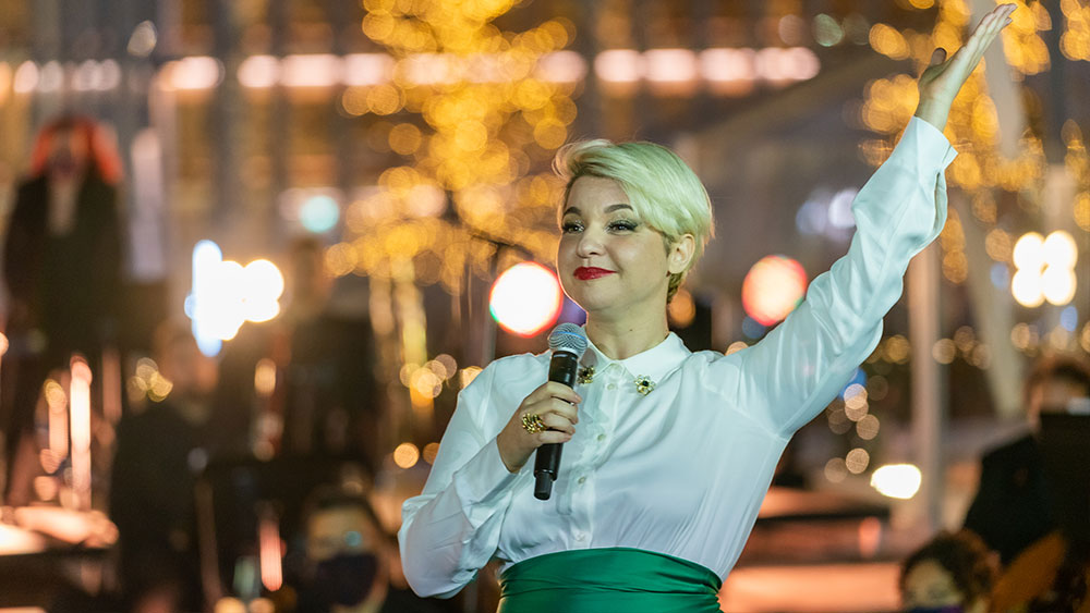 Μια γυναίκα που κρατάει μικρόφωνο σηκώνει το χέρι της με χαρά