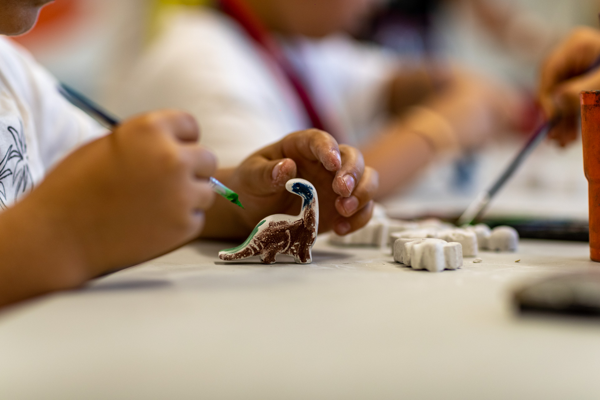 Ένα μικρό αγόρι ζωγραφίζει ένα κεραμικό δεινόσαυρο 