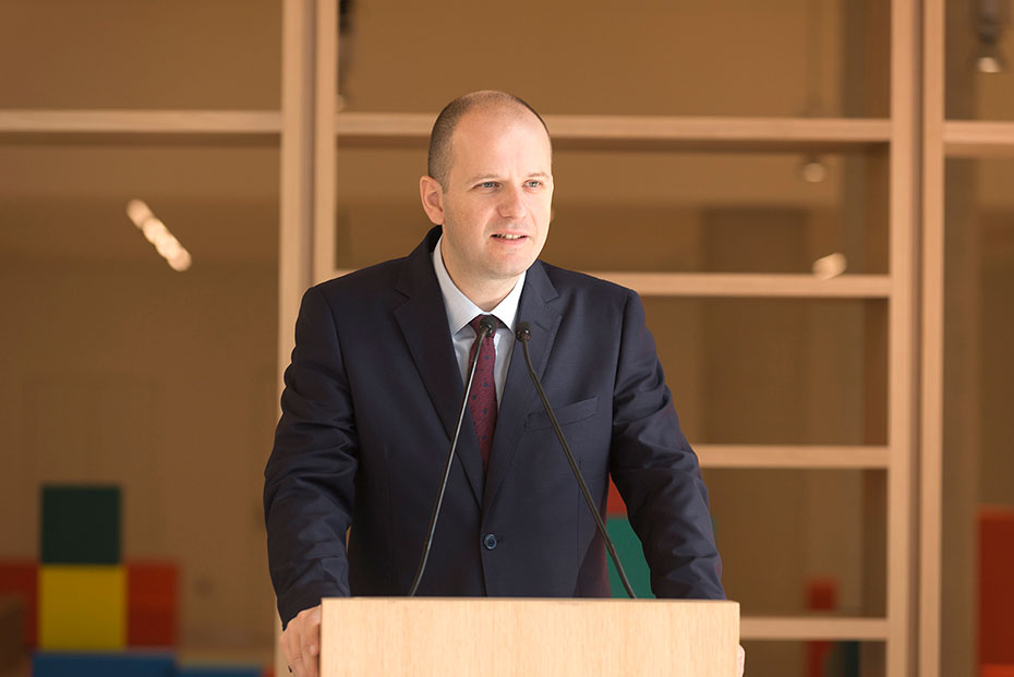 Ένας άνδρας χαμογελάει ενώ βγάζει λόγο σε ένα βήμα