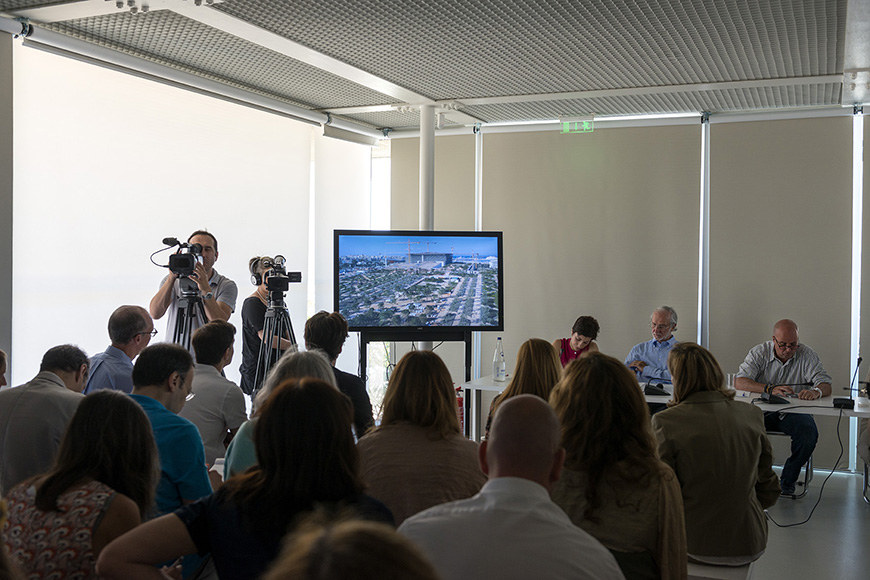 Φωτογραφία που δείχνει τον κόσμο να παρακολουθεί την εικόνα που προβάλλεται σε μια οθόνη κατά τη διάρκεια μιας ομιλίας 