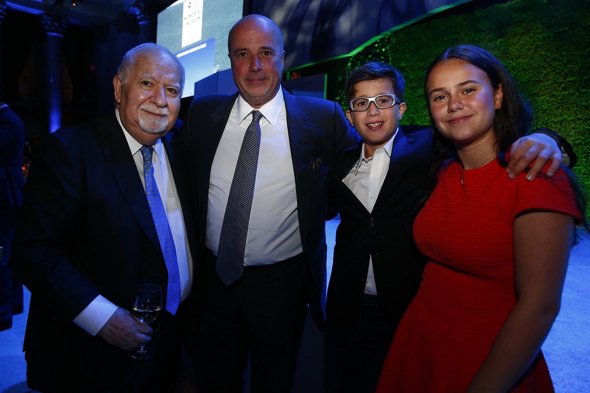 Andreas Dracopoulos, President of the Stavros Niarchos Foundation, embraces a man and two young children for a commemorative photo 