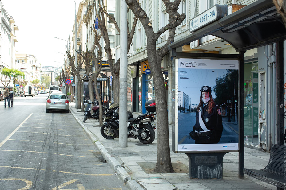 Φωτογραφία που δείχνει μία στάση λεωφορείου στον δρόμο στην οποία διαφημίζεται το iMEdD