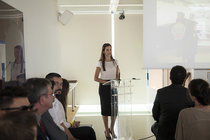 Μια γυναίκα βγάζει λόγο στο βήμα και το κοινό από κάτω την παρακολουθεί