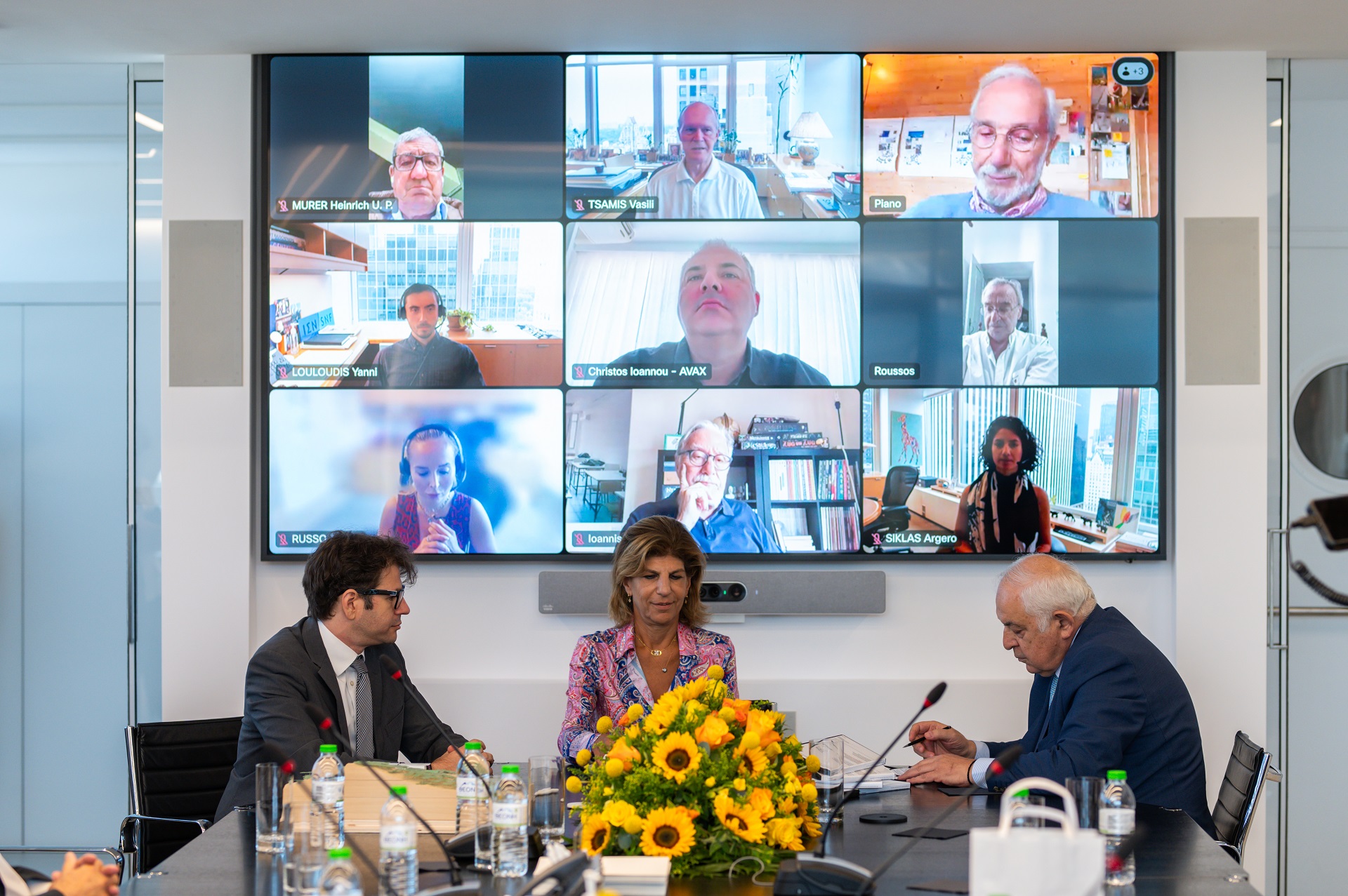 Δύο άντρες και μια γυναίκα μπροστά από ζωντανή σύνδεση με άλλα μέλη του Ιδρύματος Σταύρος Νιάρχος, υπογράφουν για την κατασκευή των τριών νέων νοσκομείων Ίδρυμα Σταύρος Νιάρχος 