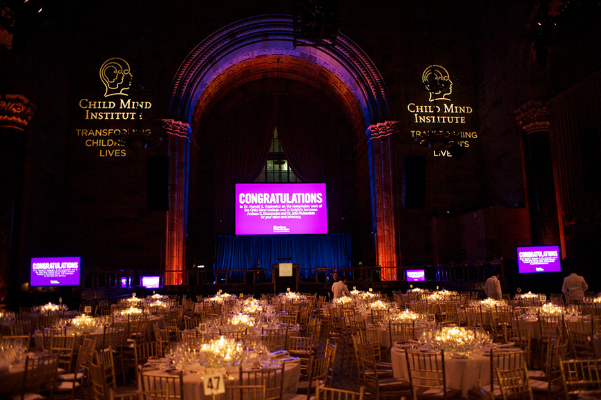 Φωτογραφία από έναν χώροδιαμορφωμένο με τραπέζια και σκηνή έτοιμο να υποδεχθεί μια δεξίωση 