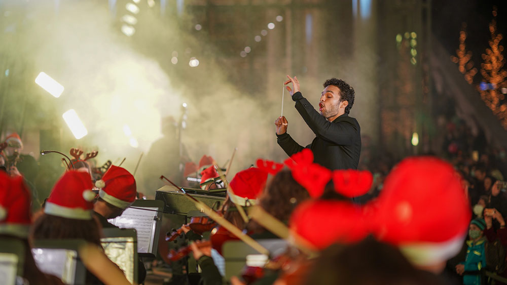 Ένας άνδρας διευθύνει μια ορχήστρα με χριστουγεννιάτικα σκουφιά στο Κέντρο Πολιτισμού Ίδρυμα Σταύρος Νιάρχος