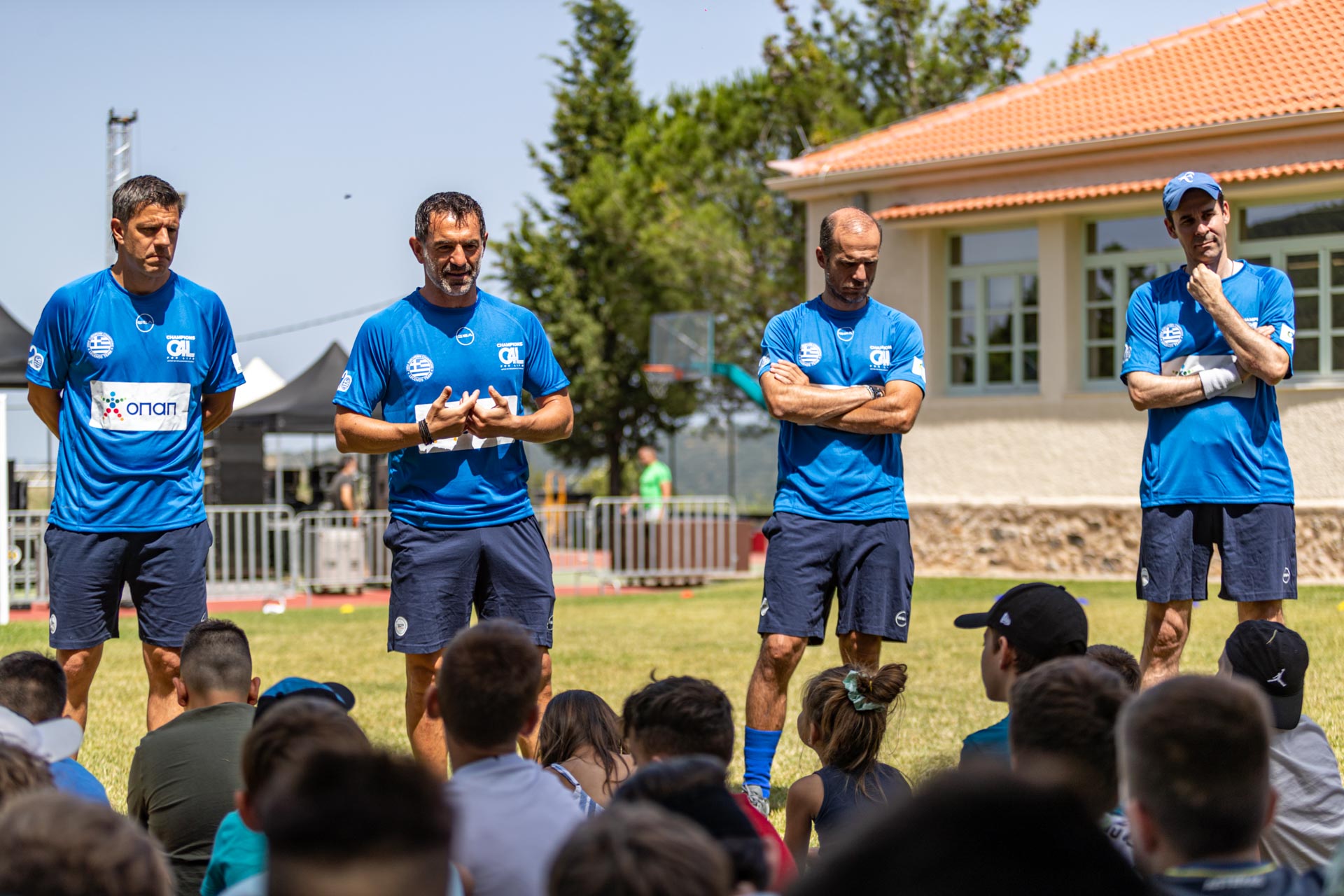 Τέσσερις προπονητές μιλούν σε μία ομάδα παιδιών 