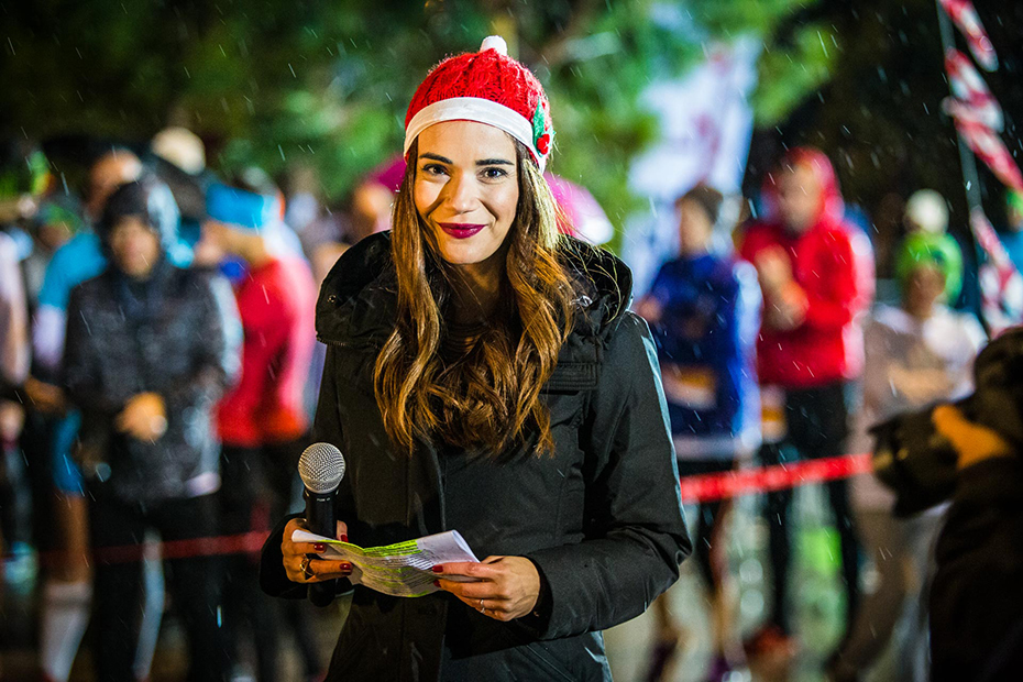 Μια γυναίκα με χριστουγεννιάτικο καπέλο χαμογελάει και κοιτάζει στην κάμερα