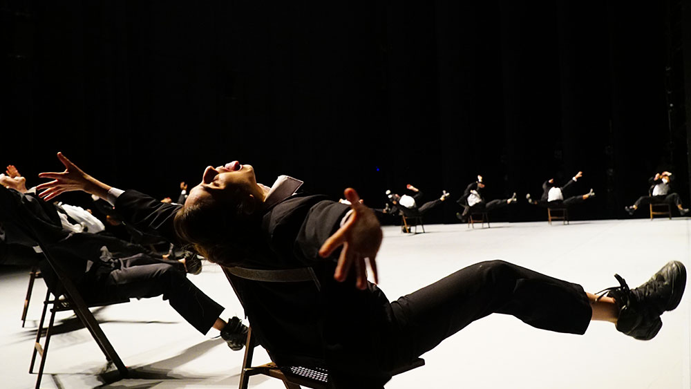 Πολλοί άνθρωποι καθονται σε κύκλο και τεντώνουν τα χέρια και τα πόδια τους ως μέρος μιας παράστασης