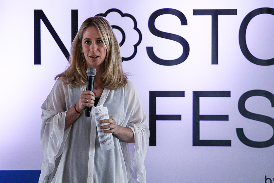 Μια γυναίκα δίνει λόγο μπροστά από έναν τοίχο που γράφει 