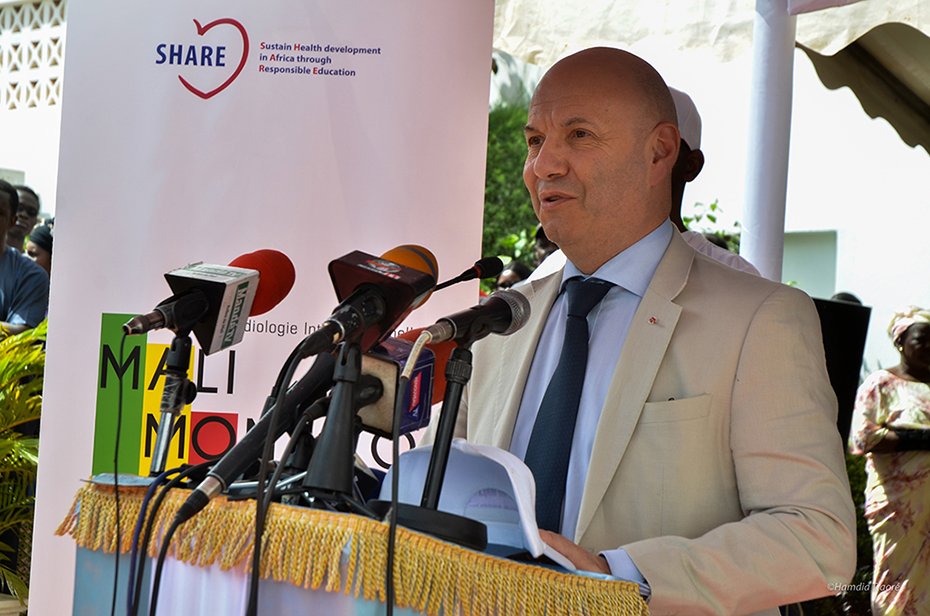 Ένας άντρας μιλάει στο βήμα ενώ δίπλα του υπάρχει ένα banner το οποίο γράφει 