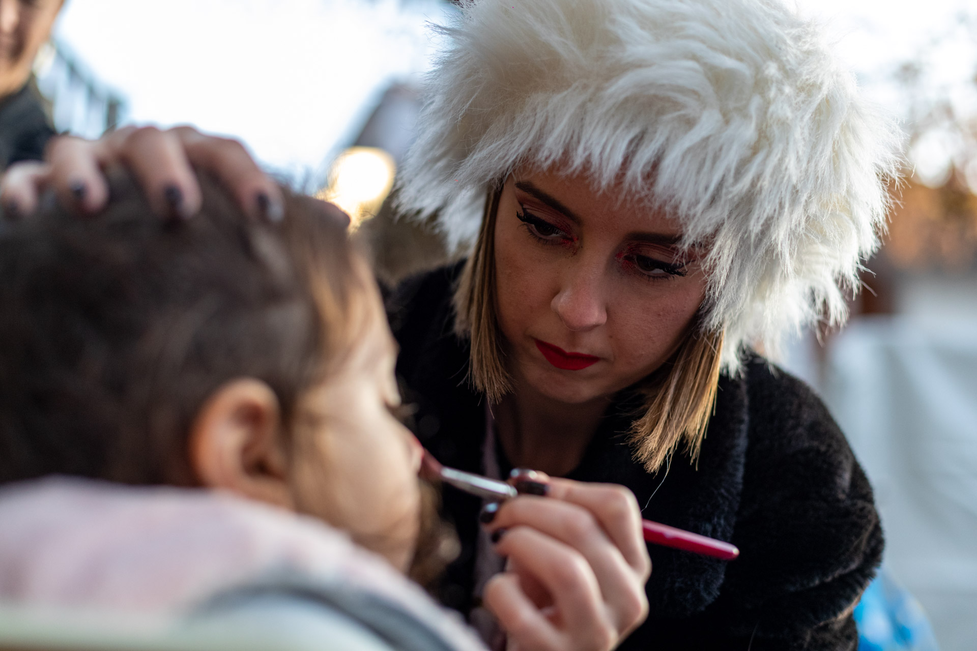 Μια γυναίκα που κάνει face painting, βάφει τη μύτη ενός μικρού κοριτσιού.