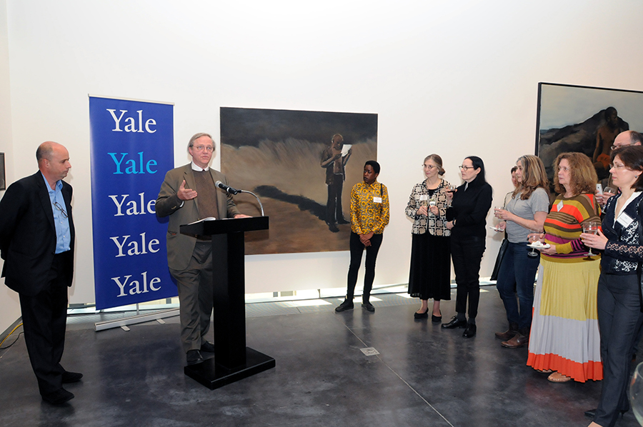 Κοντινή φωτογραφία που δείχνει έναν άντρα να μιλάει στο βήμα και δίπλα του να στέκεται ο Αντρέας Δρακόπουλος, Πρόεδρος του Ιδρύματος Σταύρος Νιάρχος και το κοινό να στέκεται και να τους παρακολουθεί 