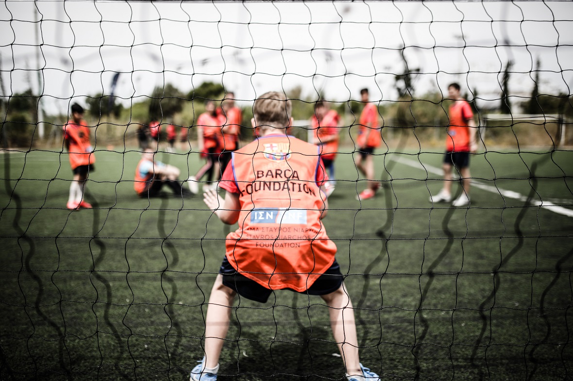 Ένα μικρό αγόρι παίζει ως τερματοφύλακας μπροστά από το δίχτυ σε ένα γήπεδο ποδοσφαίρου