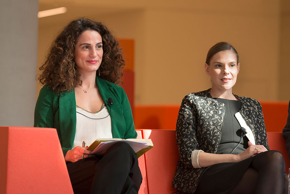 Δύο γυναίκες κάθονται και χαμογελούν με μικρόφωνα προσαρτημένα στις μπλούζες τους