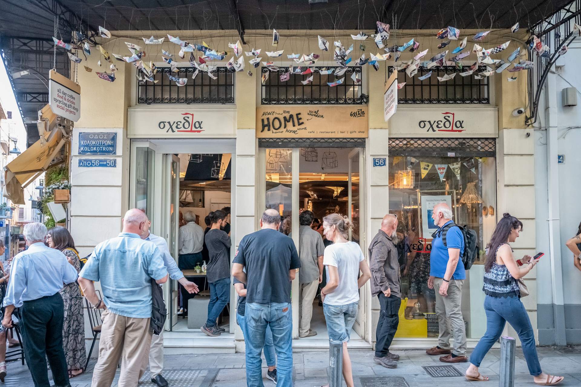 Ομάδα ανθρώπων στέκεται έξω από εστιατόριο της πόλης, κουβεντιάζοντας και απολαμβάνοντας την αστική ατμόσφαιρα.