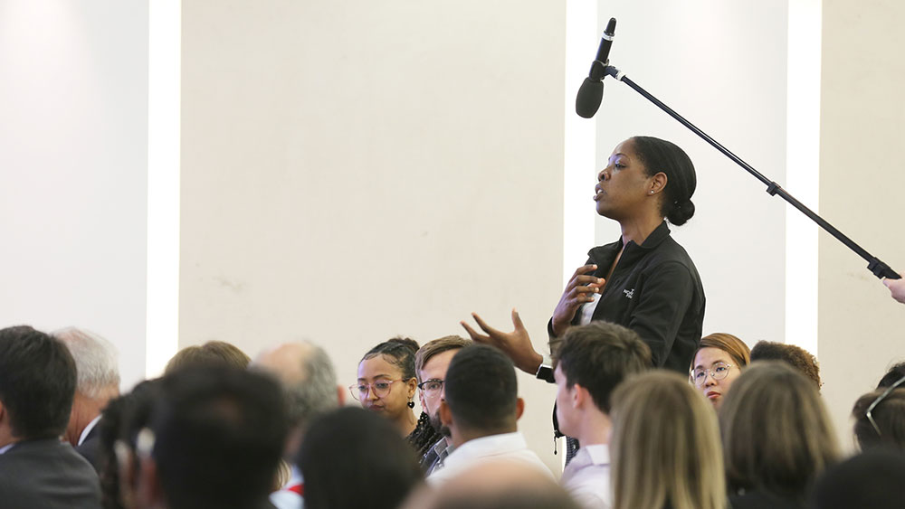 Μια γυναίκα στέκεται όρθια και μιλάει με πάθος στη μέση ενός καθισμένου κοινού