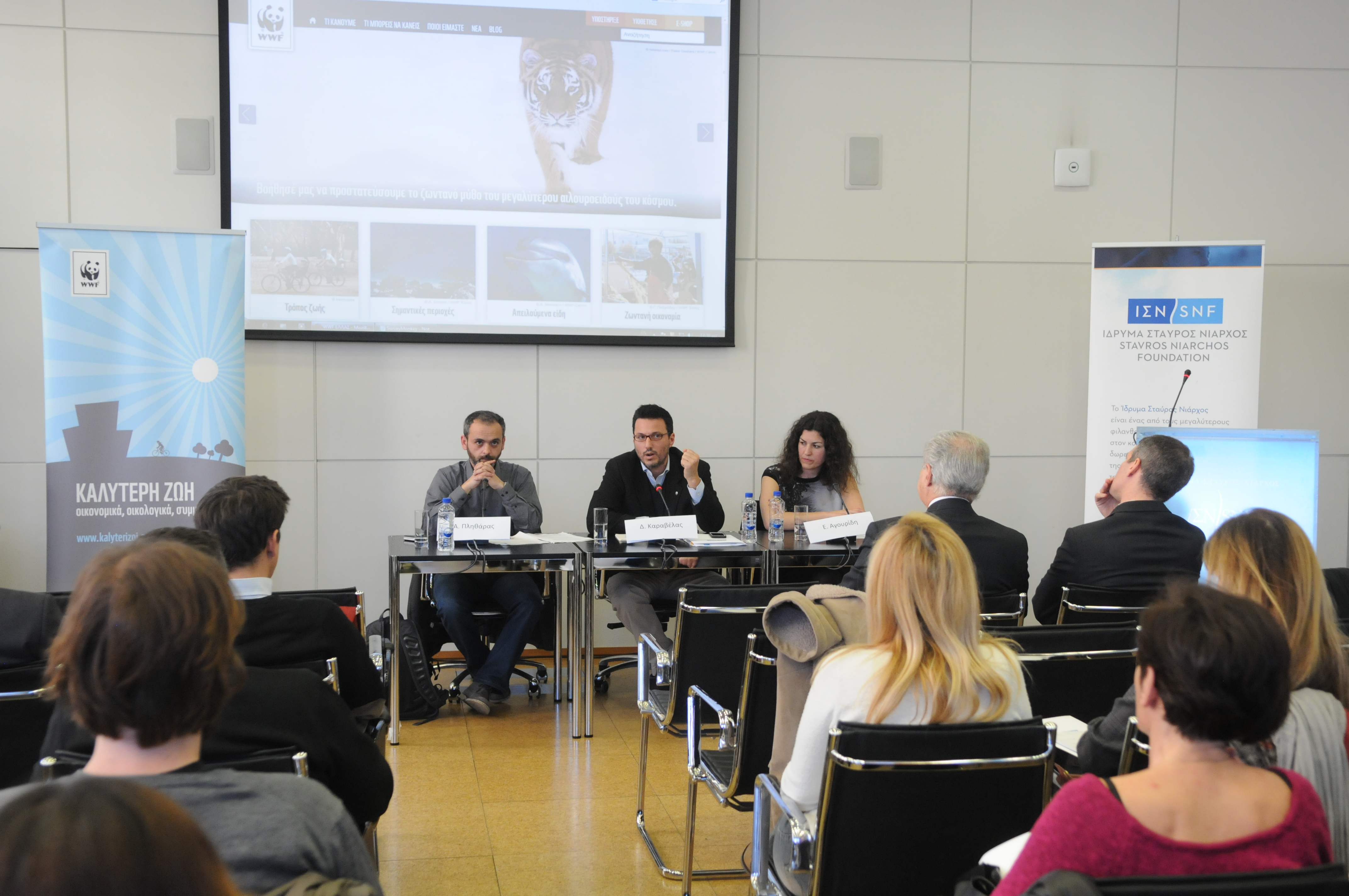 Τρία άτομα κάθονται σε ένα τραπέζι συνεδριάσεων και κάνουν μια παρουσίαση