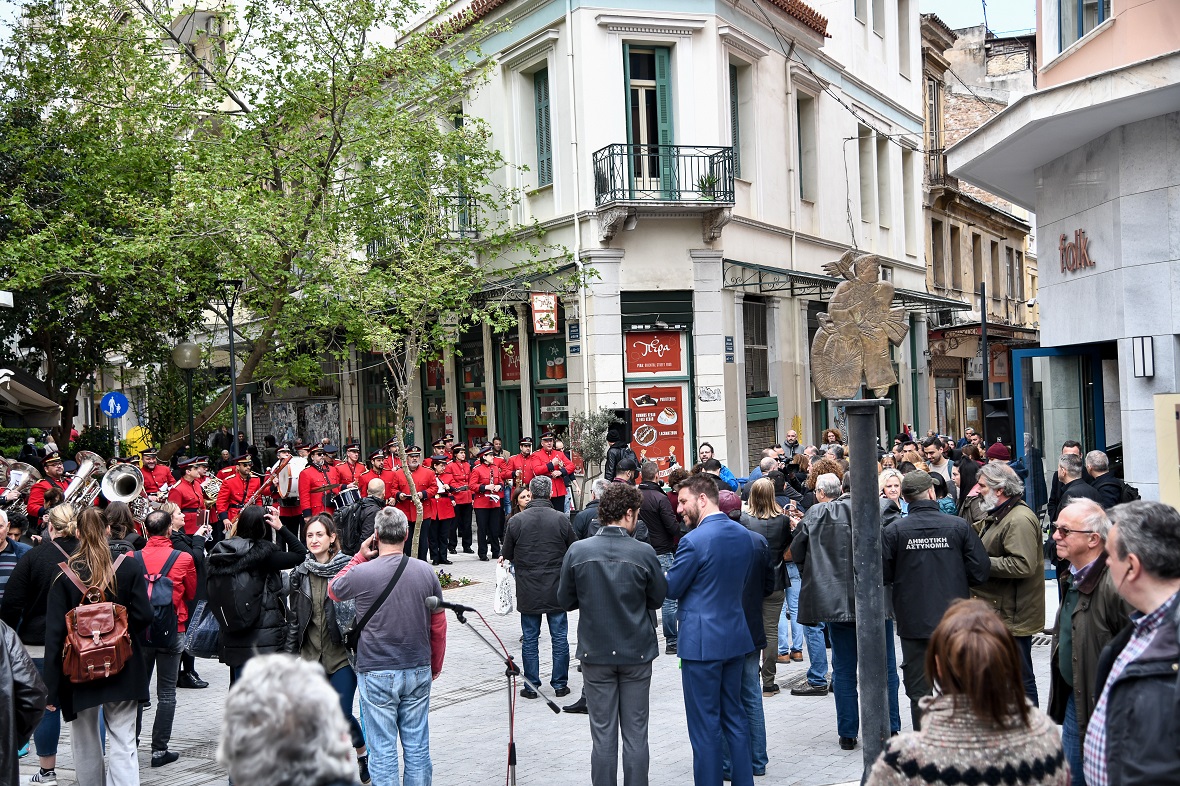 Πλήθος ανθρώπων μαζεμένο στον δρόμο βλέπουν την μπάντα που παίζει 