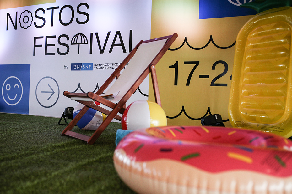 Ένα μέρος της σκηνής στο Summer Nostos Festival που έχει μια καρέκλα γκαζόν, ένα φουσκωτό ντόνατ και μια μπάλα θαλάσσης σε τεχνητό γρασίδι 