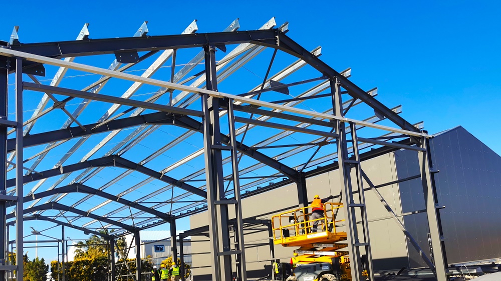 Τα σίδερα με τα οποία σχηματίζεται η μορφή ενός κτηρίου και οι εργάτες που προσπαθούν να τα στερεώσουν μεταξύ τους 