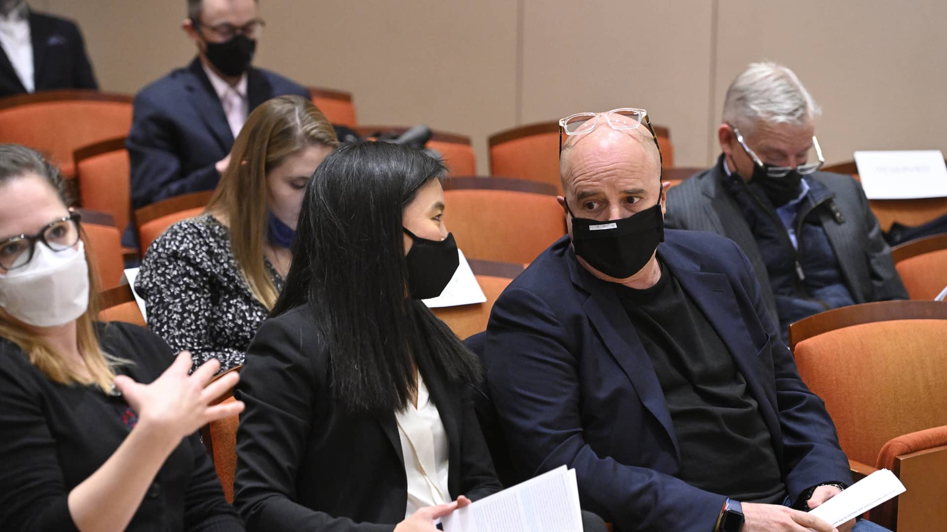 Ο Αντρέας Δρακόπουλος, Πρόεδρος του Ιδρύματος Σταύρος Νιάρχος, κάθεται σε καρέκλα και ακούει τη γυναίκα που κάθεται δίπλα του και του μιλάει  