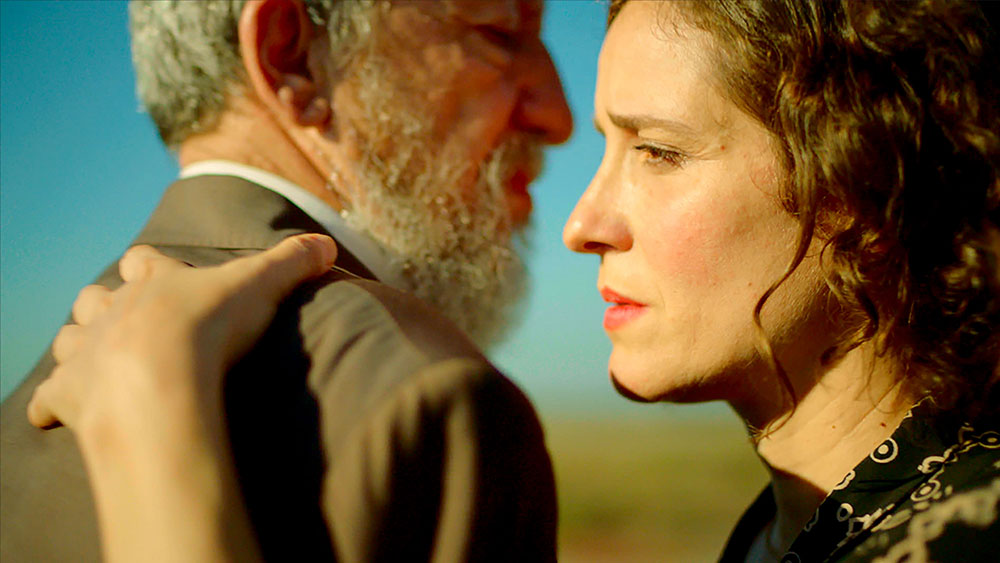 Μια γυναίκα και ένας άντρας στέκονται αντικριστά και η γυναίκα τον ακουμπάει στον ώμο