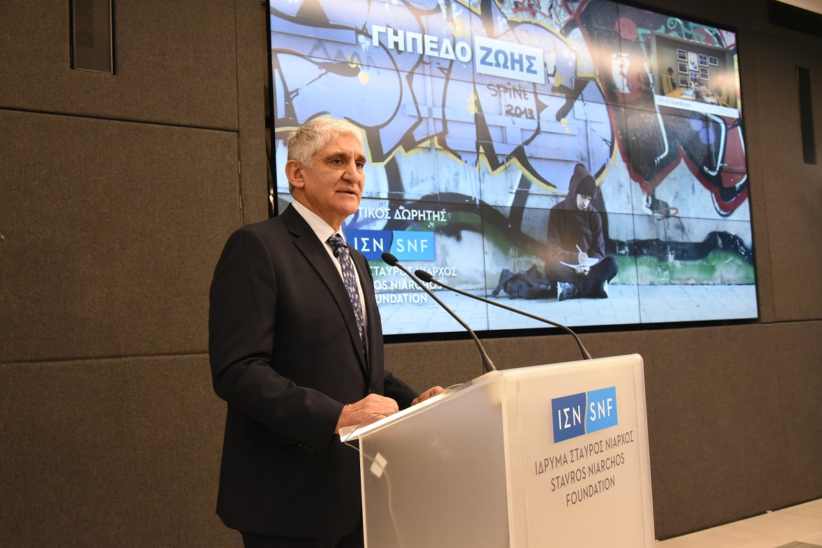 Κοντινή φωτογραφία ενός άντρα που μιλάει στο βήμα του Ιδρύματος Σταύρος Νιάρχος και δίπλα του στην οθόνη γράφει ΓΗΠΕΔΟ ΖΩΗΣ ΙΔΡΥΤΙΚΟΣ ΔΩΡΗΤΗΣ ΙΔΡΥΜΑ ΣΤΑΥΡΟΣ ΝΙΑΡΧΟΣ 