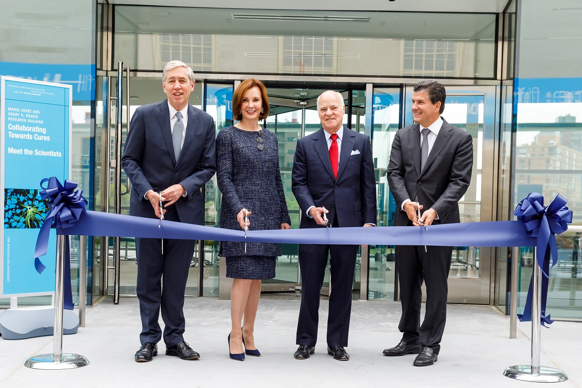 Τρεις άντρες και μια γυναίκα στέκονται όρθιοι μπροστά από μια κορδέλα εγκαινίων και είναι έτοιμοι να την κόψουν 