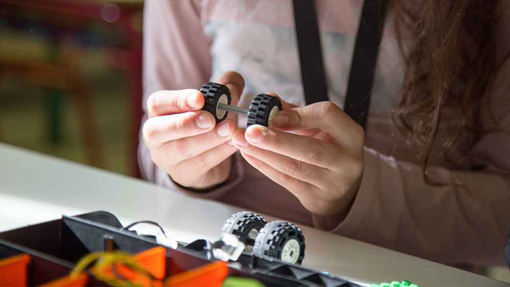 Δύο γυναικεία χέρια ενώνουν δύο ρόδες LEGO 