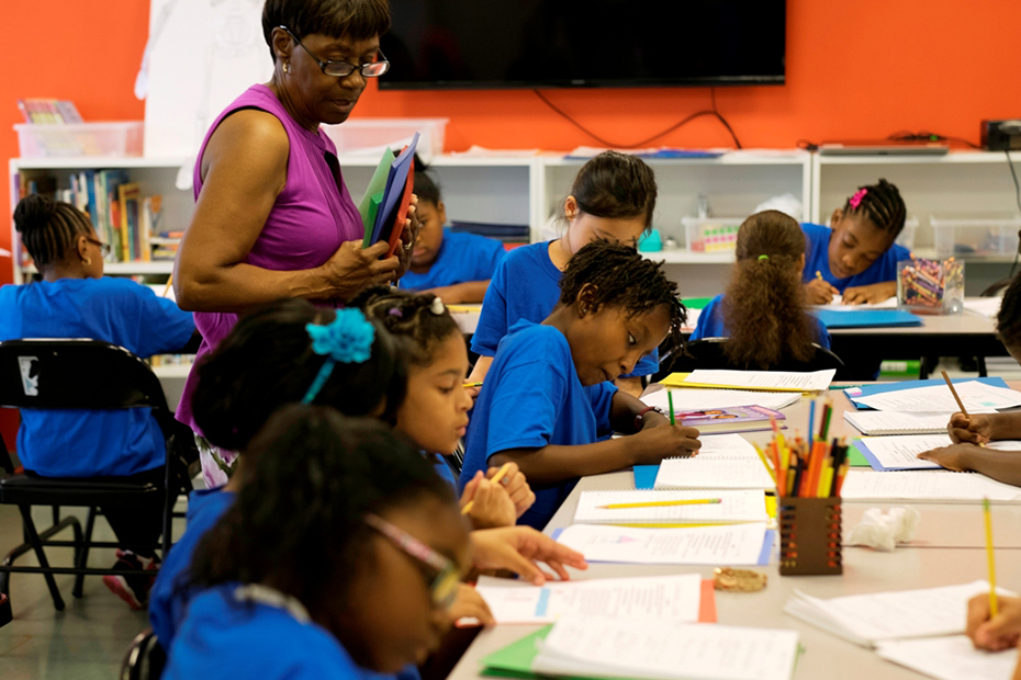 Ένας δάσκαλος παρακολουθεί τα παιδιά που κάθονται σε μια αίθουσα μελετώντας και γράφοντας