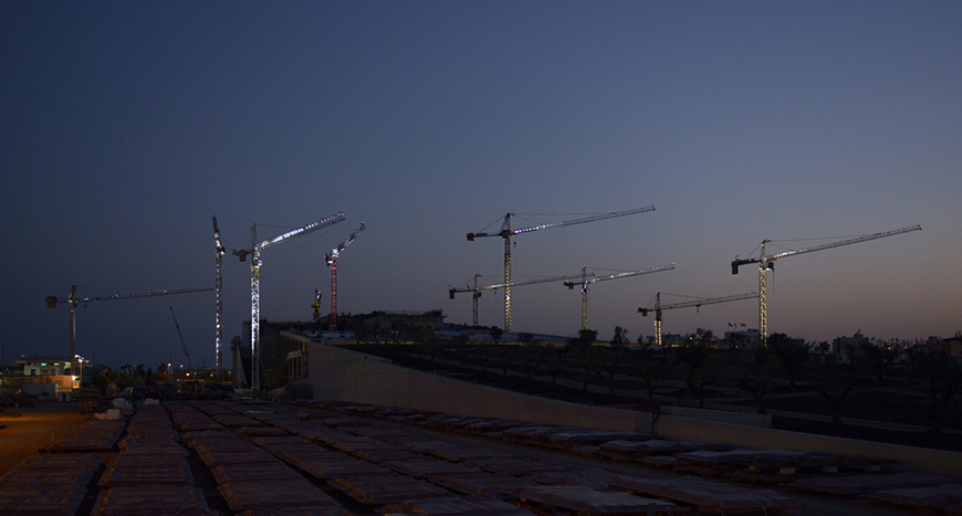 Μακρινή φωτογραφία που δείχνει γερανούς τοποθετημένους μέσα σε ένα εργοτάξιο