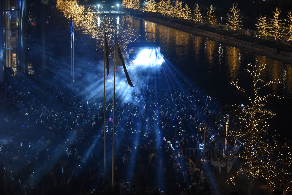 Φωτογραφία τραβηγμένη με drone η οποία δείχνει πλήθος ανθρώπων να παρακολουθούν μια συναυλία και τα φωτορυθμικά της σκηνής 