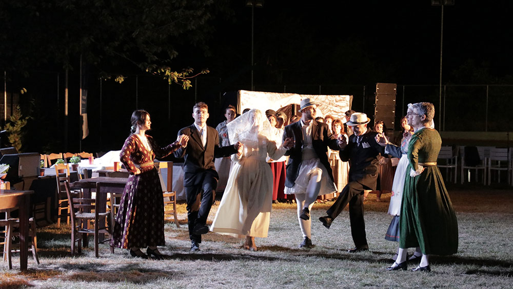 Μια ομάδα νέων φοράει παραδοσιακές στολές και χορεύουν παραδοσιακό χορό 