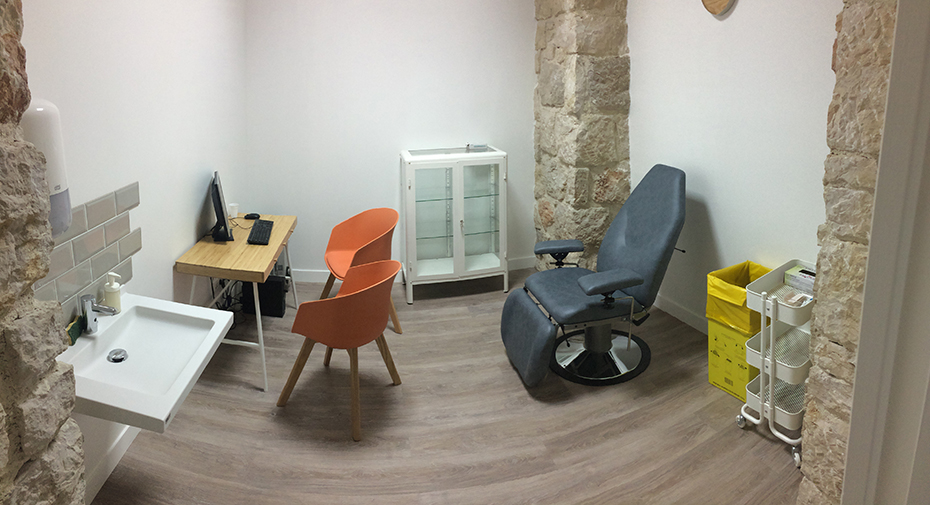 Ένα μικρό δωμάτιο στο οποίο υπάρχει μια μεγάλη καρέκλα, ένα πολύ μικρό γραφείο με έναν υπολογιστή και ένας νιπτήρας 