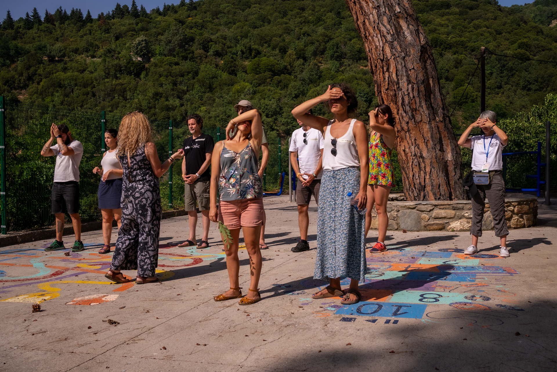 Μια ομάδα ανθρώπων στέκονται όρθιοι και μερικοί μπλοκάρουν τον ήλιο με τα χέρια τους 