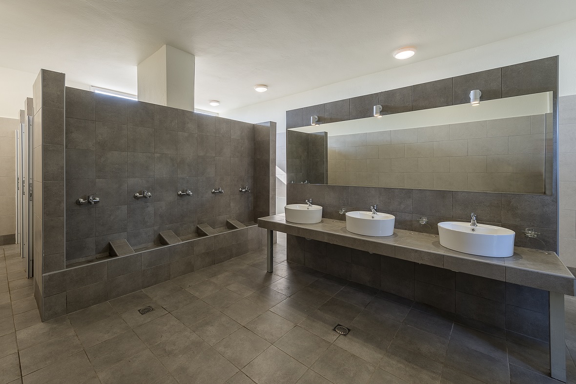 Ένα μεγάλο μπάνιο με σύγχρονες τουαλέτες, ντους, νιπτήρες και καθρέφτες.