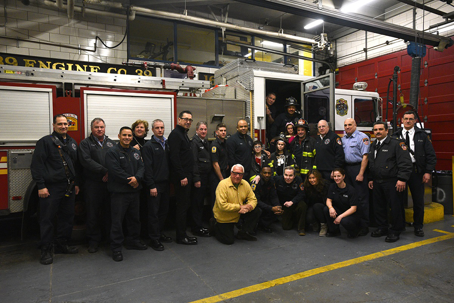 Μια ομάδα ανθρώπων στέκονται μέσα και έξω από πυροσβεστικά οχήματα και βγάζουν μια αναμνηστική φωτογραφία 