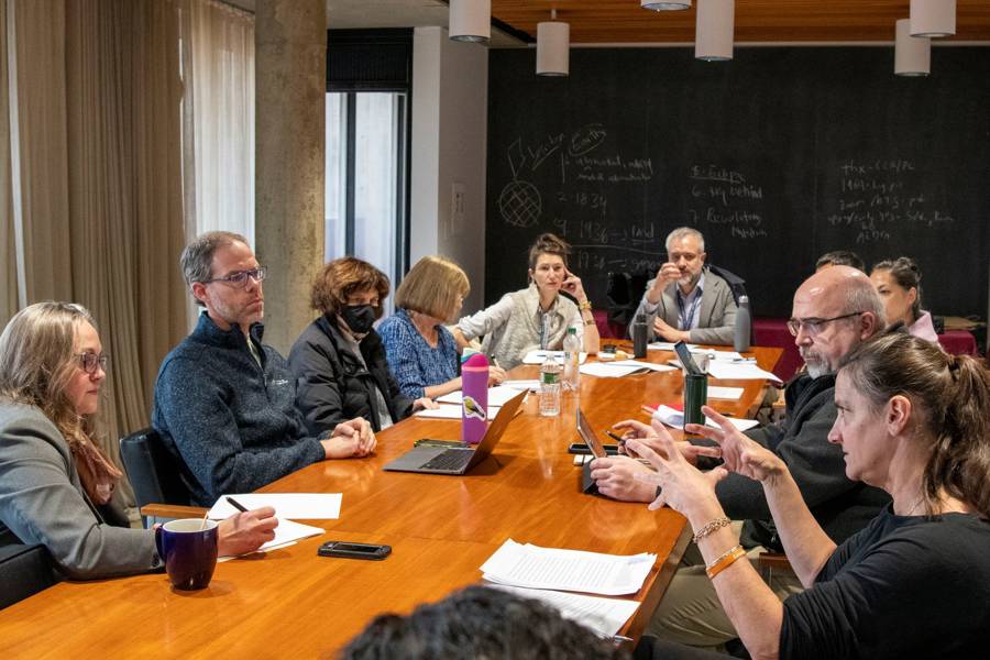 Individuals around a conference table discuss.