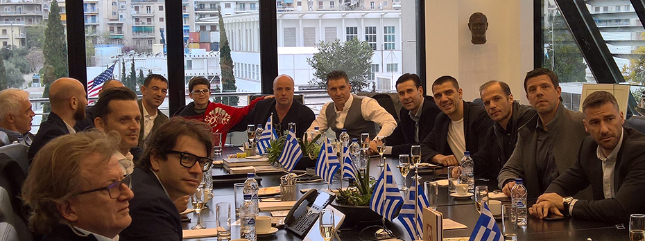 Μέλη της ελληνικής ομάδας των πρωταθλητών του Euro 2004 κάθονται σε αίθουσα συνεδριάσεων και φωτογραφίζονται με μέλη του Ιδρύματος Σταύρος Νιάρχος