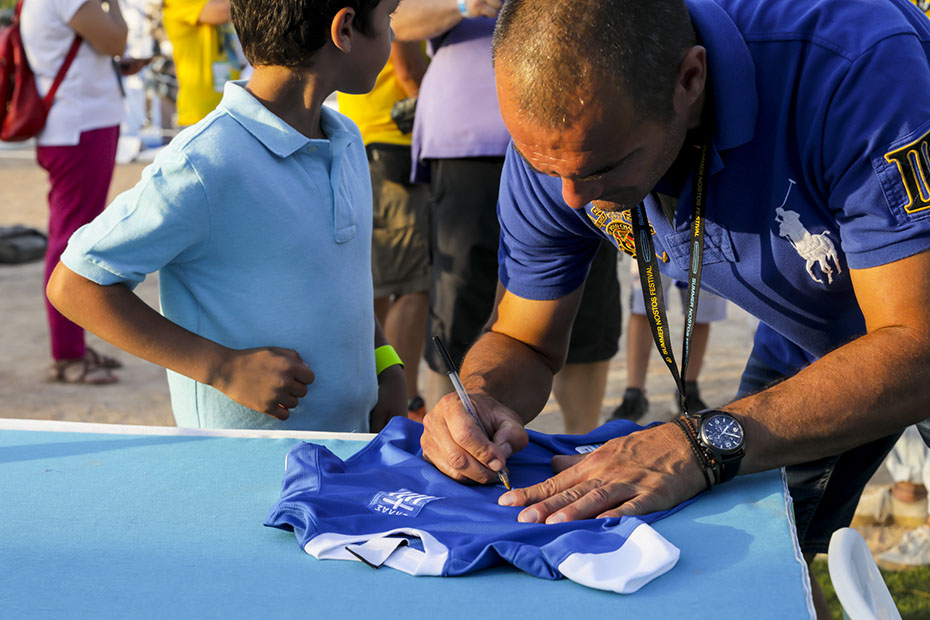 Ένας άντρας υπογράφει μια ποδοσφαιρική φανέλα της ελληνικής ομάδας ποδοσφαίρου για ένα μικρό αγοράκι 