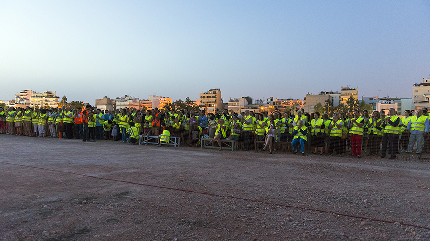 Φωτογραφία που δείχνει πλήθος ανθρώπων που φοράνε το ίδιο γιλέκο εργασίας, να είναι μαζεμένοι όλοι μαζί και να χειροκροτούν 