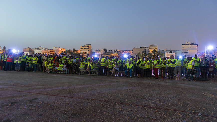 Φωτογραφία που δείχνει πλήθος ανθρώπων που φοράνε το ίδιο γιλέκο εργασίας, να είναι μαζεμένοι όλοι μαζί και να χειροκροτούν 
