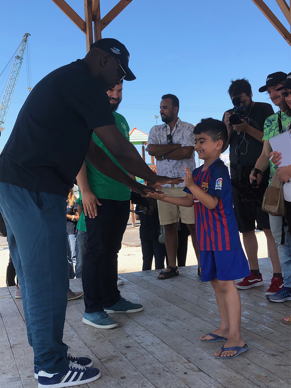 Ένας άντρας παίζει ένα παιχνίδι με ένα μικρό αγοράκι και κόσμος γύρω τους τους κοιτά