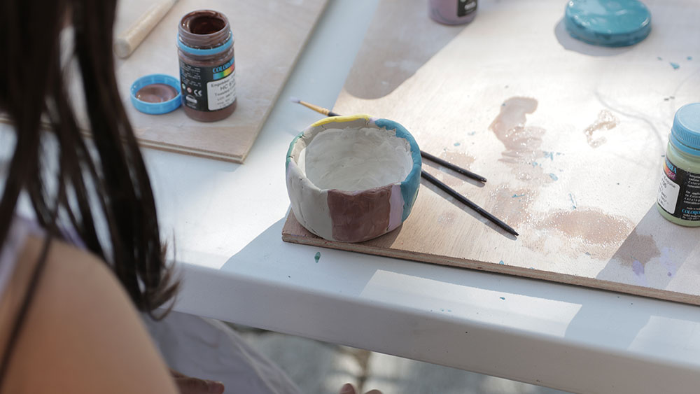 Μια κοπέλα κοιτάει το κεραμικό μπολάκι που ζωγράφισε 